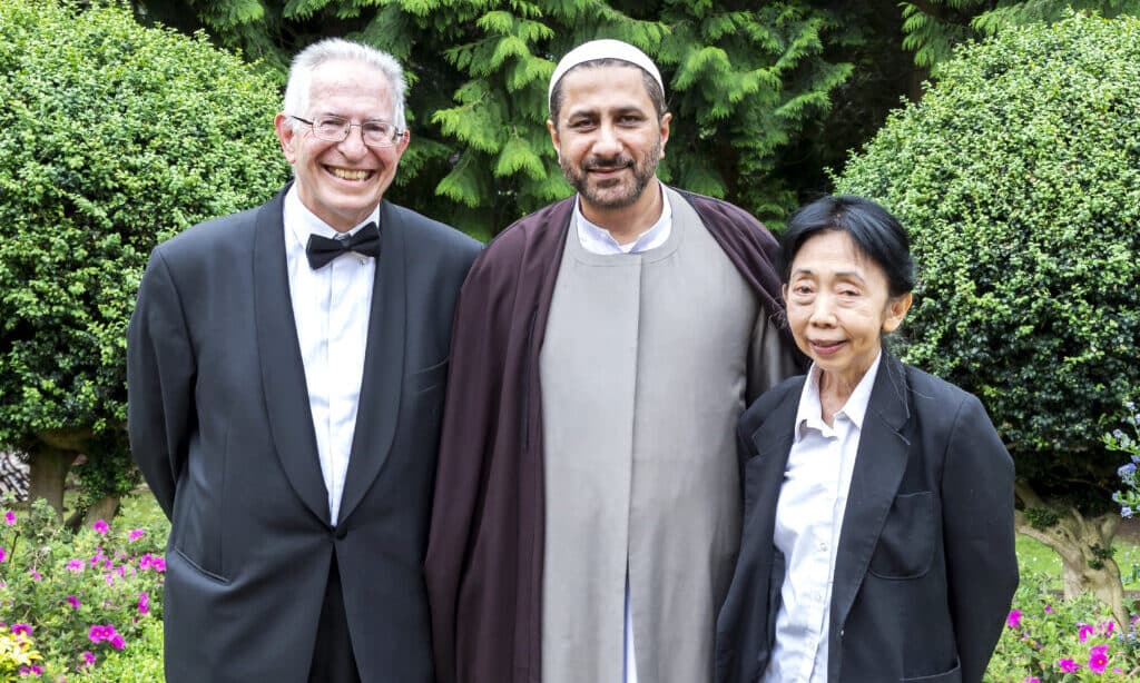 An Al-Mahdi Institute scholar with international academic guests in a garden setting, highlighting the institute's commitment to interfaith dialogue and collaborative critical Islamic scholarship.